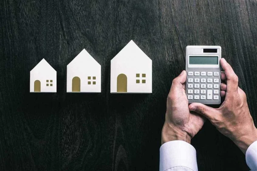houses of all sizes and a calculator implying they need to reduce taxes on property