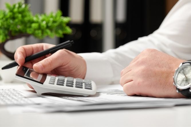 man holding a calculator and a pen